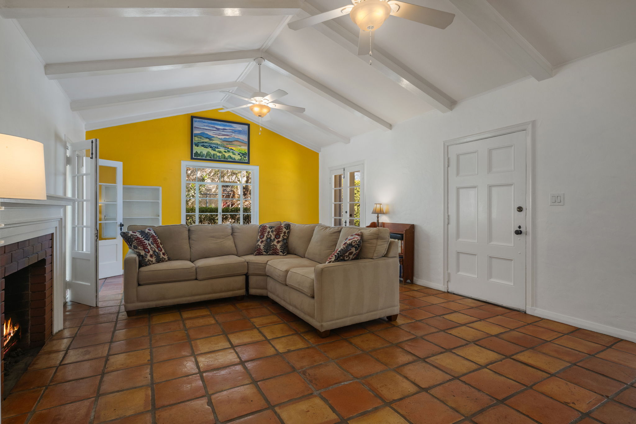 Living room with vaulted ceilings, Saltillo tile floors, and fireplace in Monterey Revival home Willo Historic District